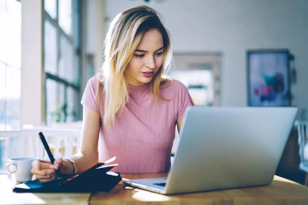 Caucasian female student with netbook computer e learning and messaging in coffee shop