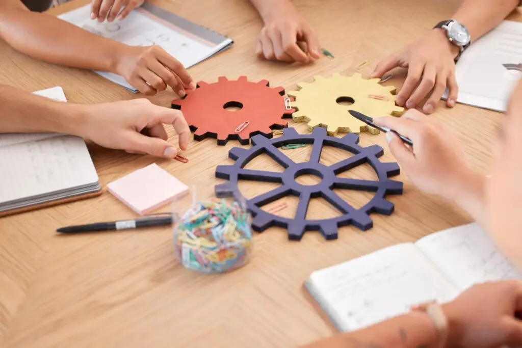 Team, strategy collaboration and gears innovation problem solving in business meeting. Corporate te